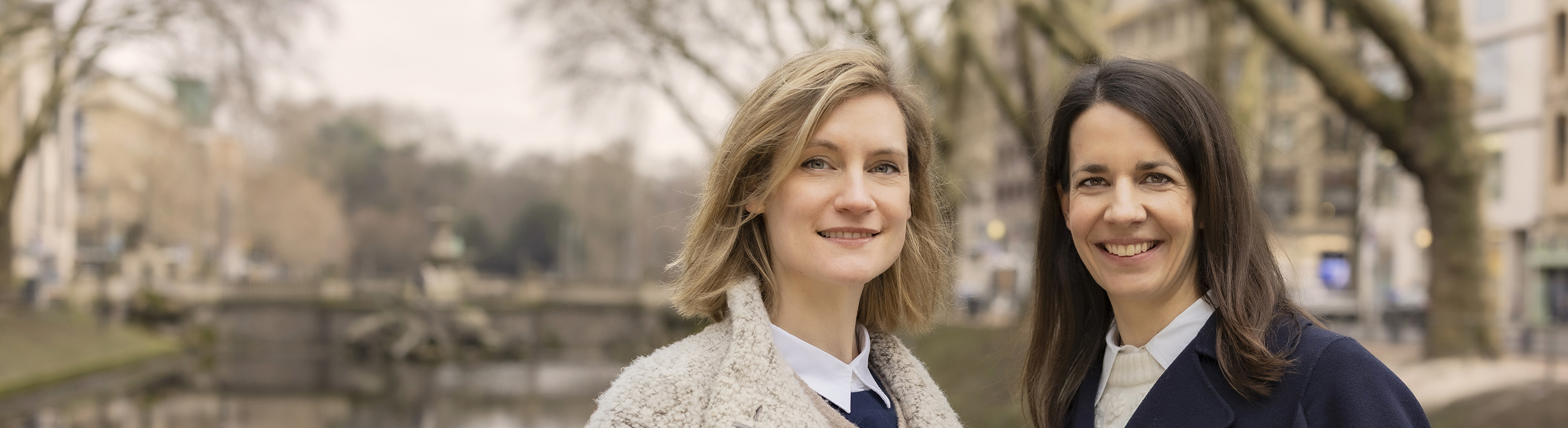 Frau Dr. Junghanns und Frau Dr. Siebeck Außenaufnahme in Düsseldorf an der Kö mit Bäumen und Gebäuden im hintergrund